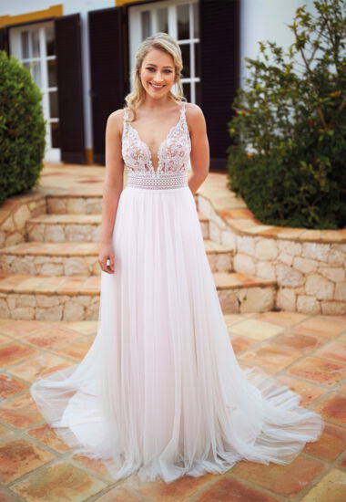 Das Brautkleid vereint Boho und Vintage Elemente, mit tiefem V-Ausschnitt und fließendem Rock aus Softtüll.